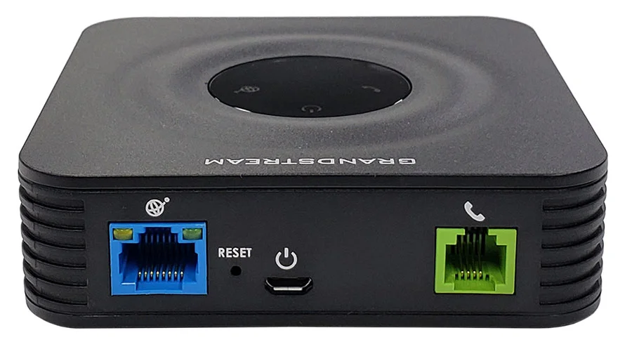 Vista trasera del adaptador de telefonía IP Grandstream HT801, mostrando un puerto Ethernet WAN (azul), un puerto para línea telefónica (verde), un botón de reinicio, y un conector de alimentación micro USB.